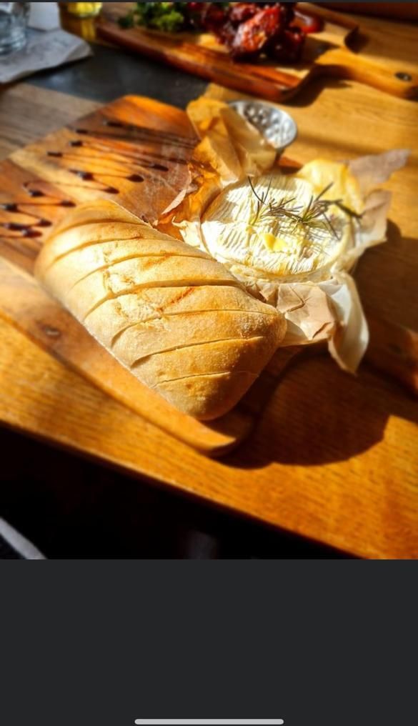 Een houten snijplank met een brood en een kaaswiel erop.