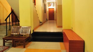 A brightly lit hallway with yellow walls, a wooden bench, and a staircase leading to another room. - Hotel Satkar (Jaipur)