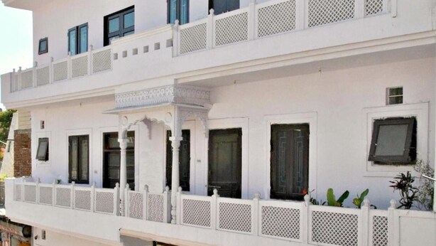 A multi-story building with balconies, a sign indicating a restaurant, and a shop on the ground floor. - Hotel Satkar (Jaipur)