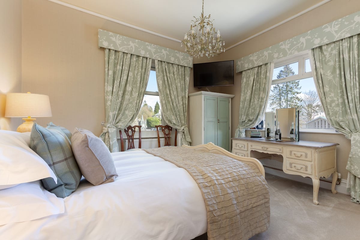 A bedroom with a bed, dresser, vanity, and a chandelier.