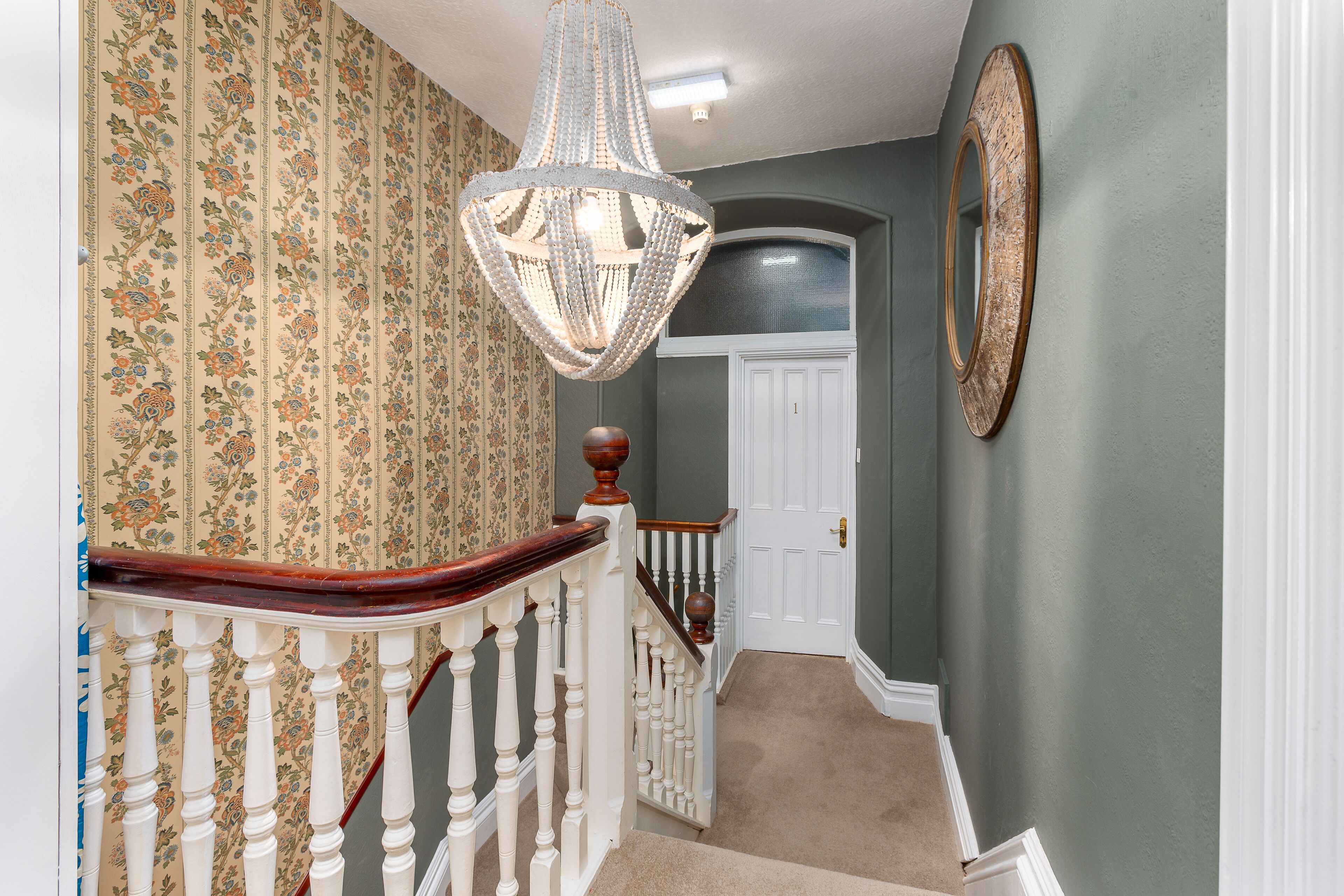 A staircase with a wooden handrail and a chandelier.
