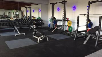A gym with weightlifting equipment, benches, and dumbbells.
