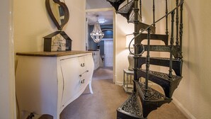 A staircase with ornate black railings and a white wall with a heart-shaped mirror. - Glencree (Windermere)