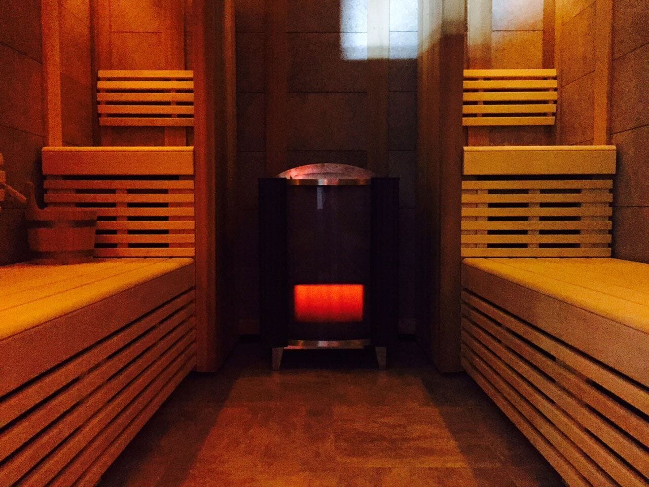 A sauna room with benches and a central heating unit.
