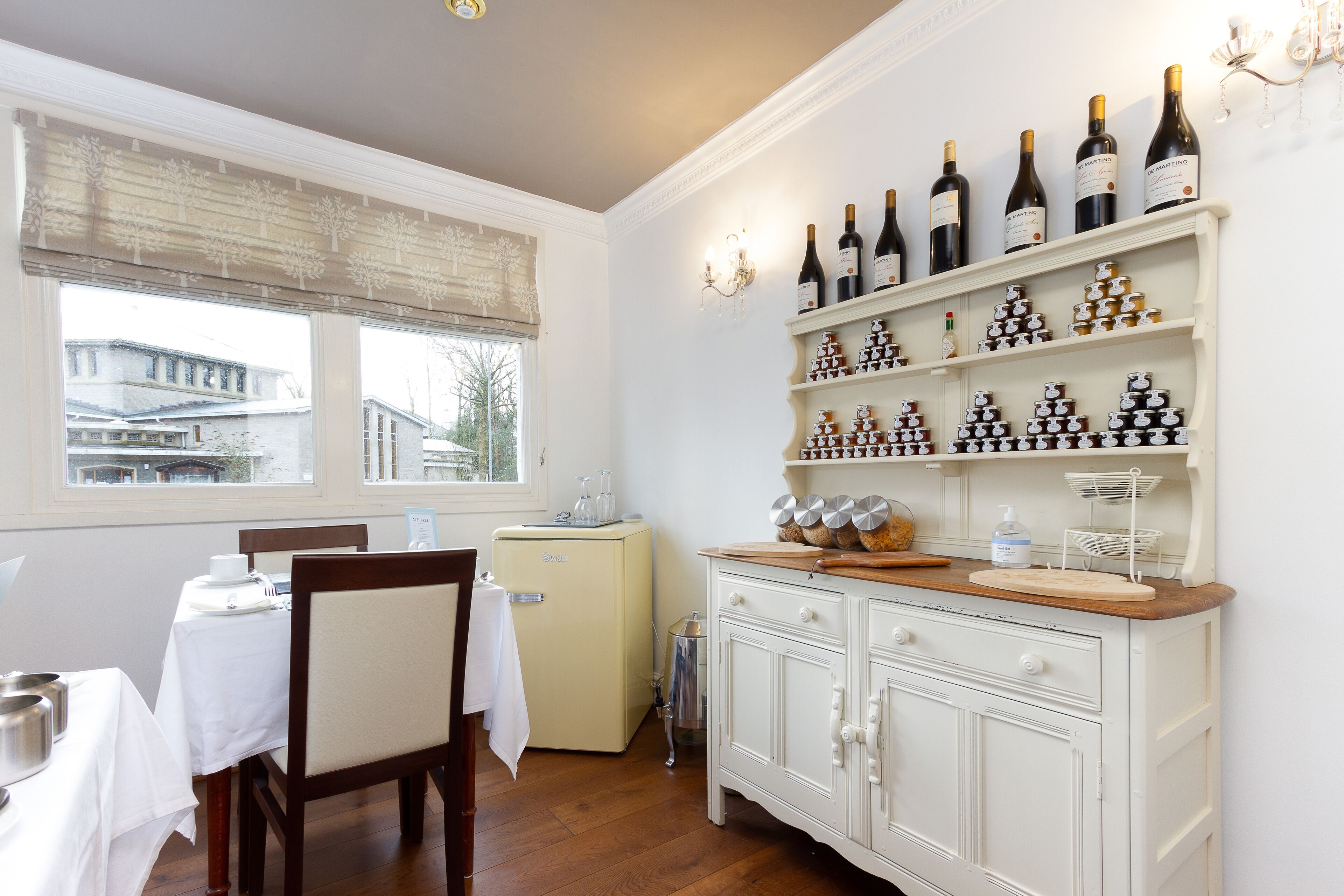 A dining area with a table set for two, a vintage refrigerator, and a wine rack with bottles.