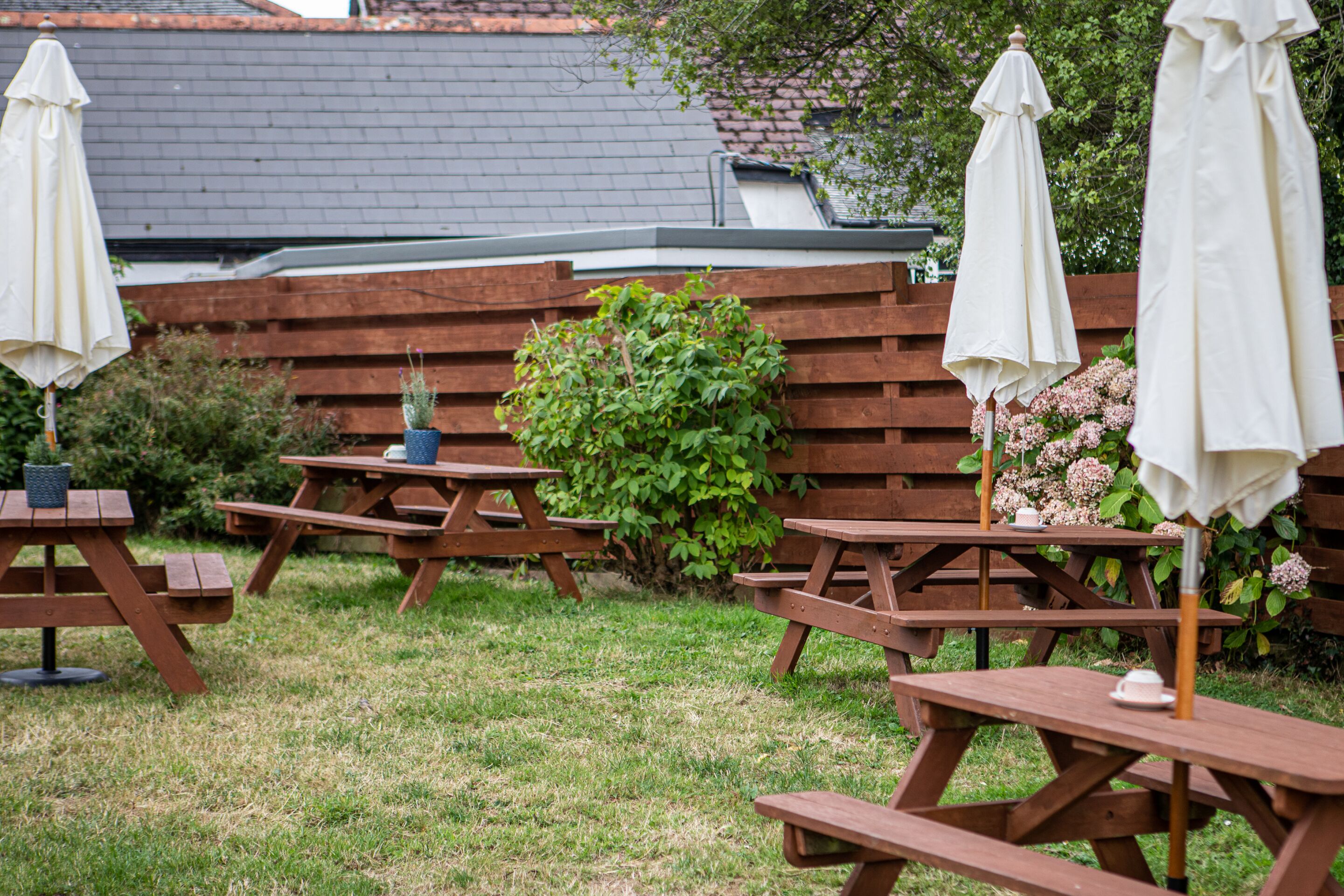 Un patio al aire libre con mesas de picnic y sombrillas blancas.