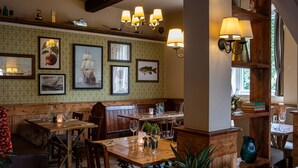 A restaurant interior with wooden tables, chairs, and a variety of framed pictures on the walls. - Three Tuns (Helston)