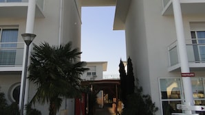 A modern building with a central atrium, a Coca-Cola sign, and directional signs for 'Accueil Reception' and 'Bâtiment ABC'. - All Suites Appart Hôtel | Bordeaux - Mérignac Aéroport (Merignac)