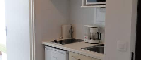 A compact kitchen with a dishwasher, a microwave, and a coffee maker.