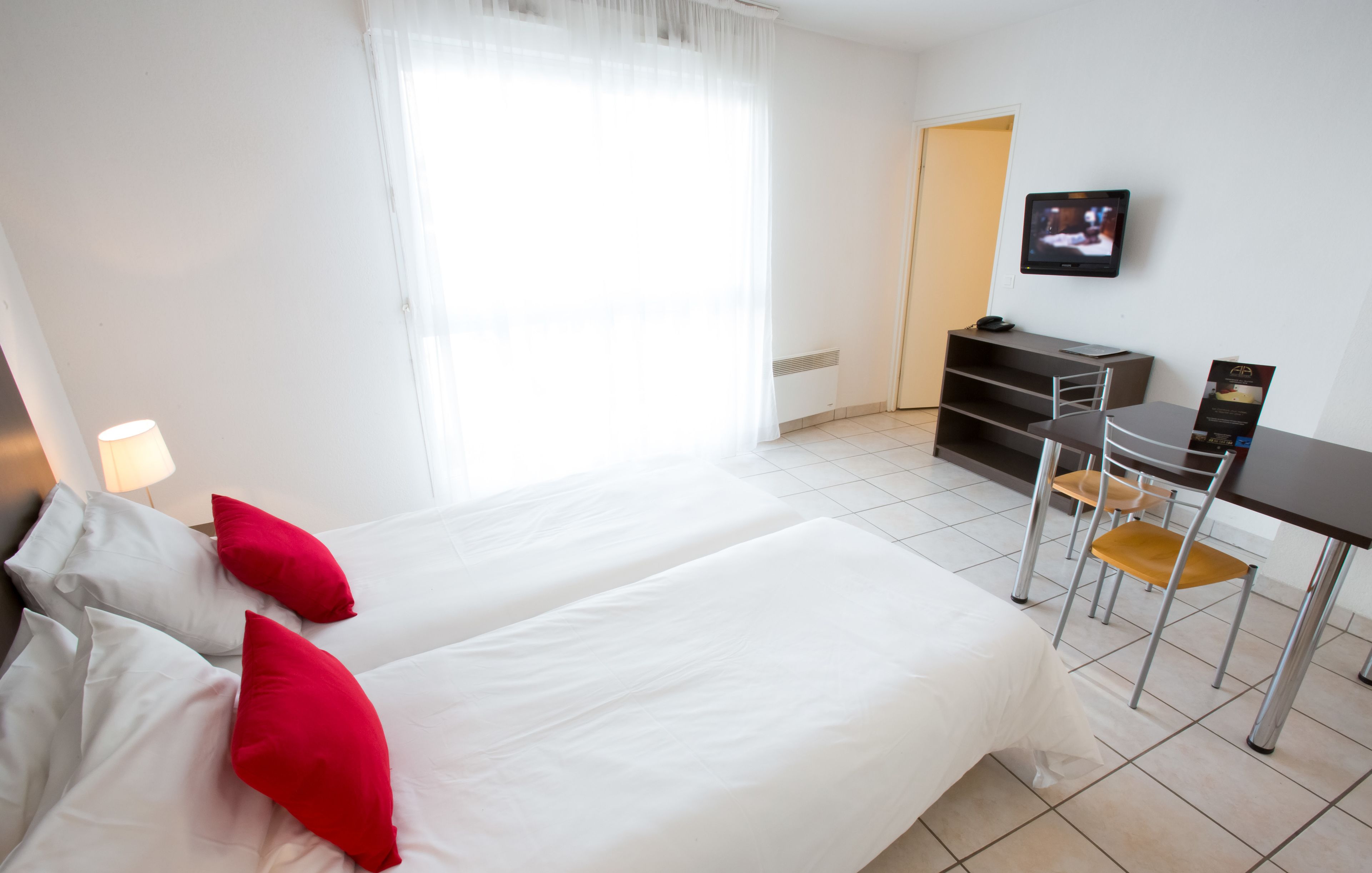 Habitación de hotel con dos camas, un escritorio y una silla.