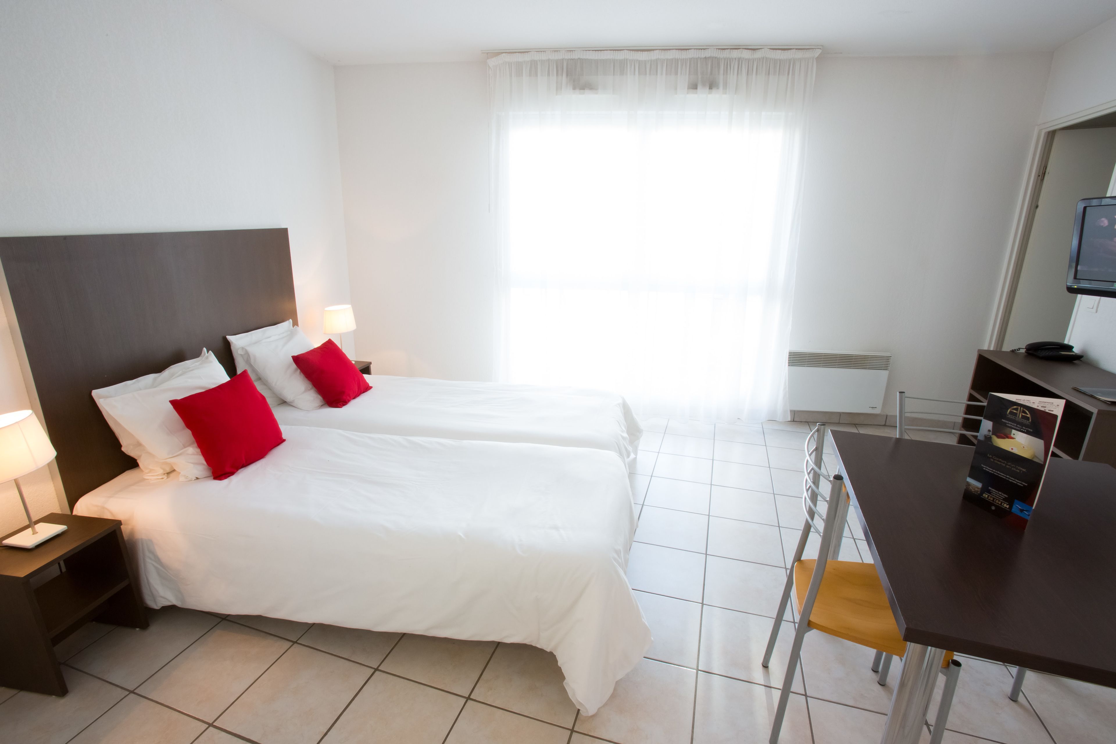Una habitación de hotel con dos camas, un escritorio y una televisión.