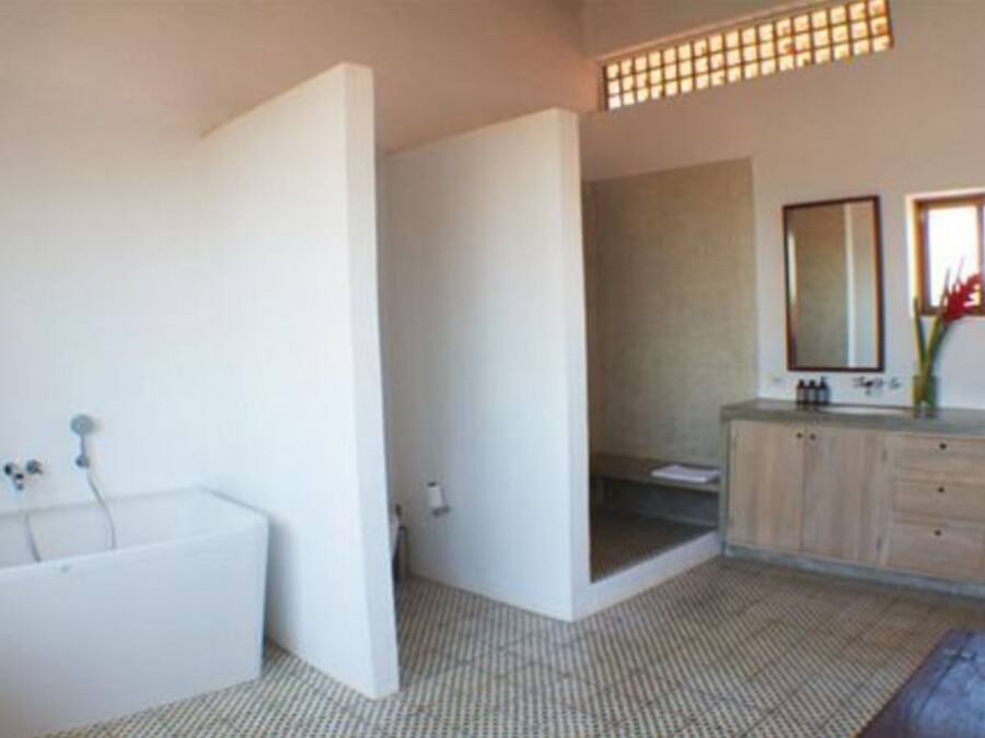 Een moderne badkamer met een bad, een douche en een wastafel met spiegel.