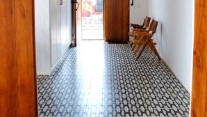 A hallway with patterned floor tiles, wooden doors, and a seating area with chairs. - Los Patios Hotel (Granada)