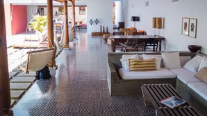 A spacious living area with a high ceiling, a dining table, and a sofa. - Los Patios Hotel (Granada)