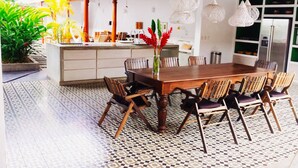 A spacious dining area with a large wooden table surrounded by chairs, a tiled floor, and hanging pendant lights. - Los Patios Hotel (Granada)