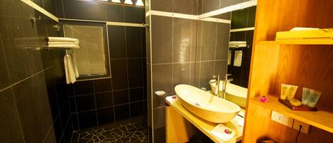 A modern bathroom with a large sink, mirror, and shower area.