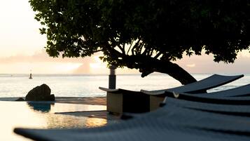 Una piscina al aire libre, sombrillas, sillones reclinables de piscina