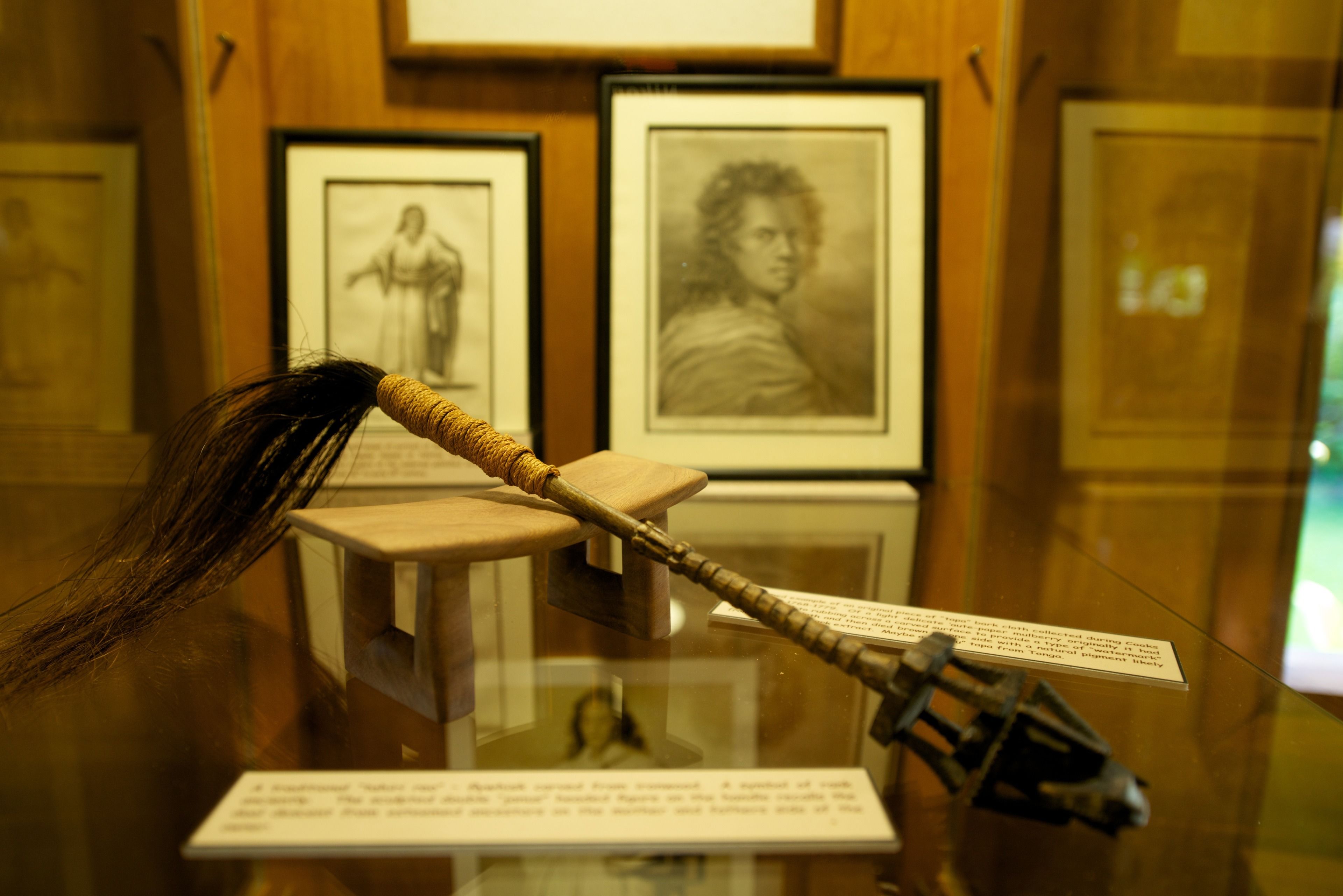 A display case with a historical artifact, framed artwork, and informational plaques.