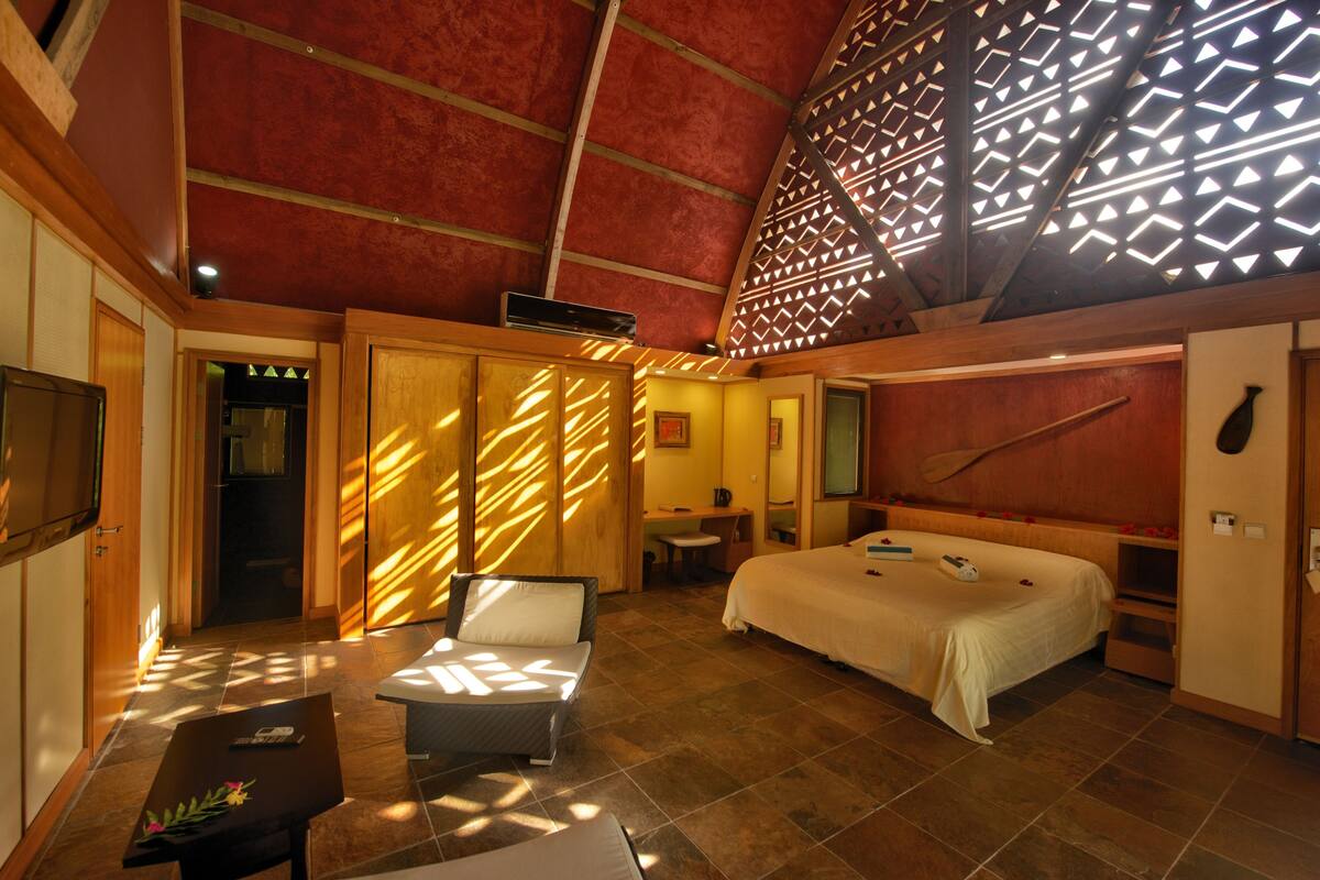 A spacious bedroom with a large bed, a sitting area with a table, and a shower area.