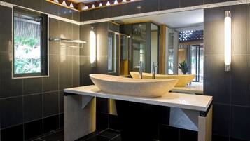 A modern bathroom with a large, oval-shaped vessel sink, a mirror, and a towel rack.