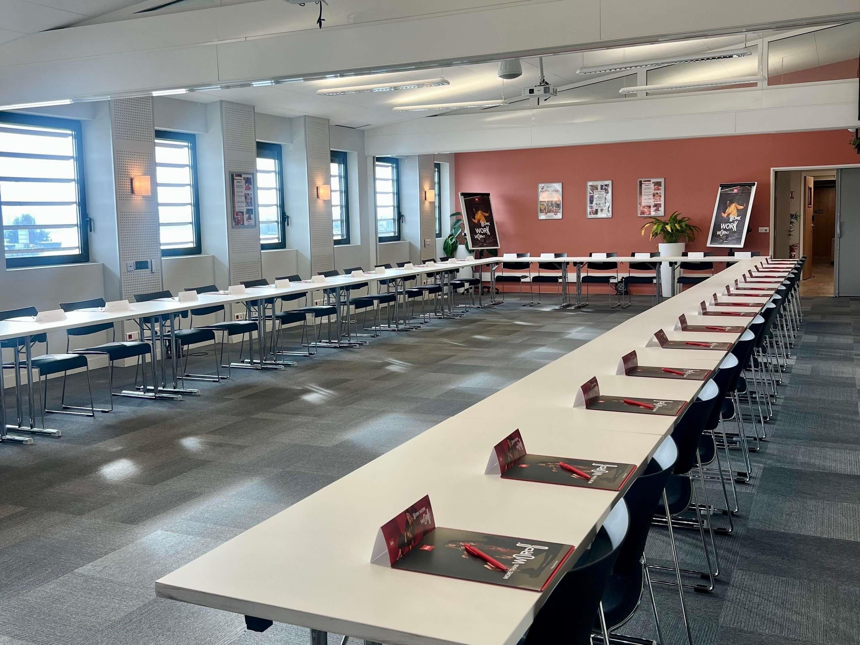 A conference room with long tables, chairs, and a red accent wall.