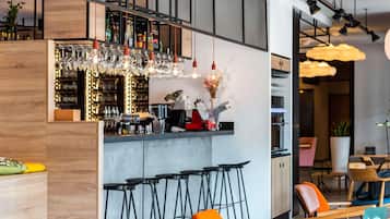 A modern bar area with a bar counter, stools, and hanging light fixtures.