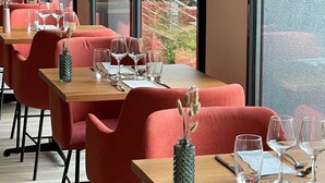 A restaurant with red chairs and tables, each set with wine glasses, water glasses, and cutlery. - ibis Lyon Sud Oullins (Oullins)
