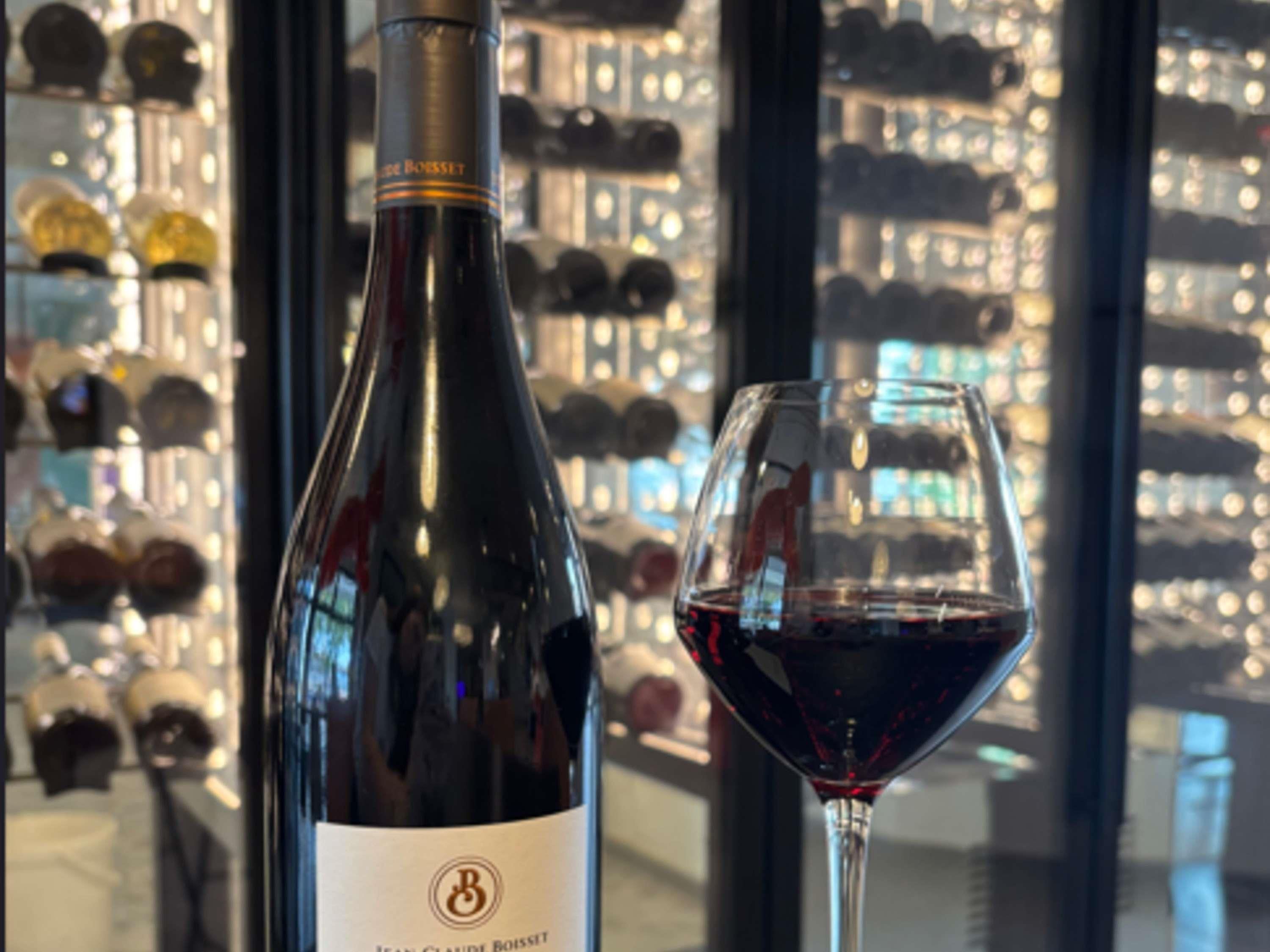 A wine bottle and glass in a bar setting with a city view.