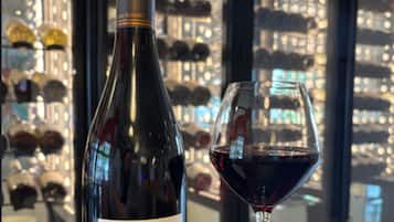 A wine bottle and glass in a bar setting with a city view.