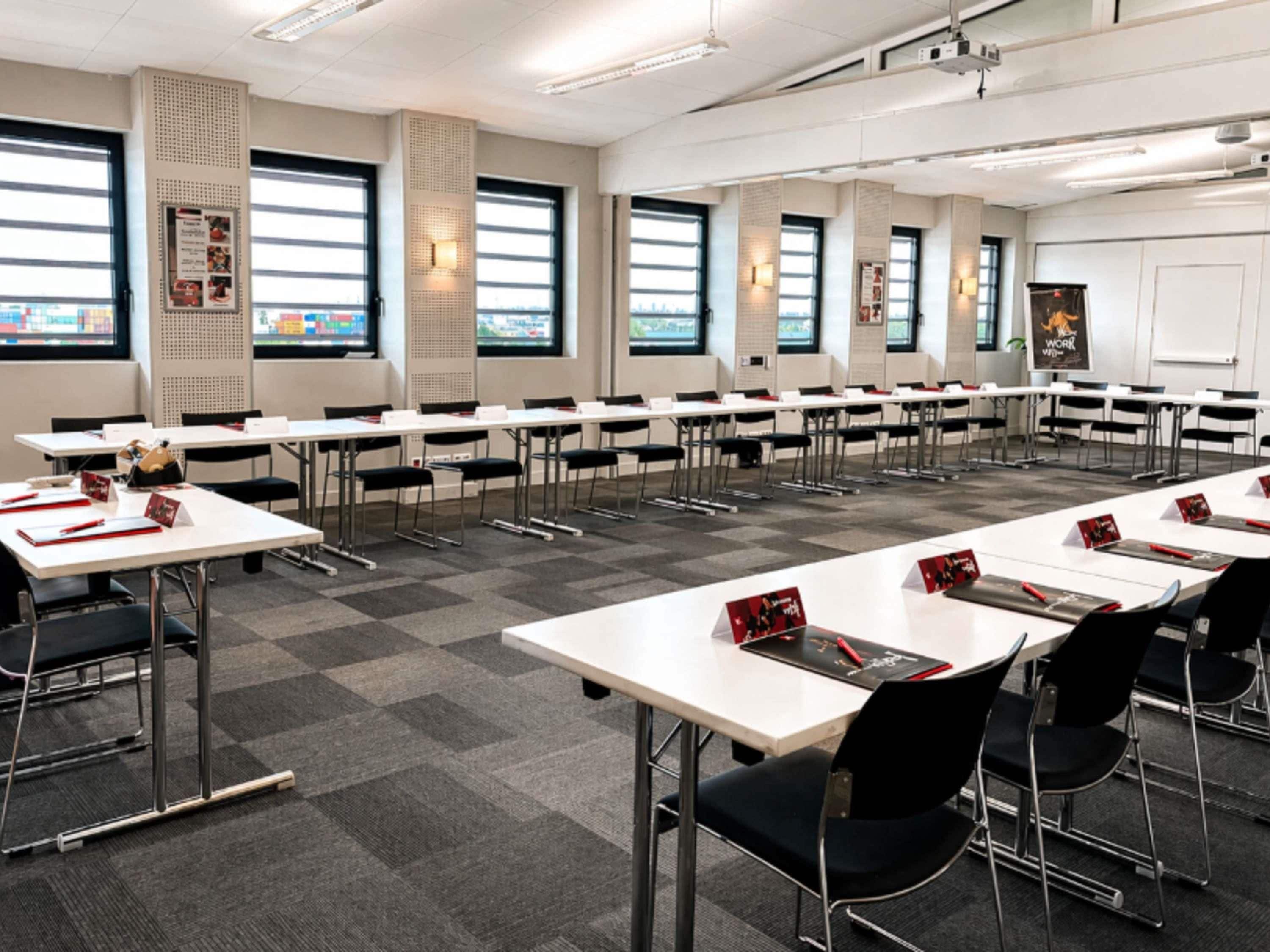 A conference room with multiple tables, chairs, and a projector screen.