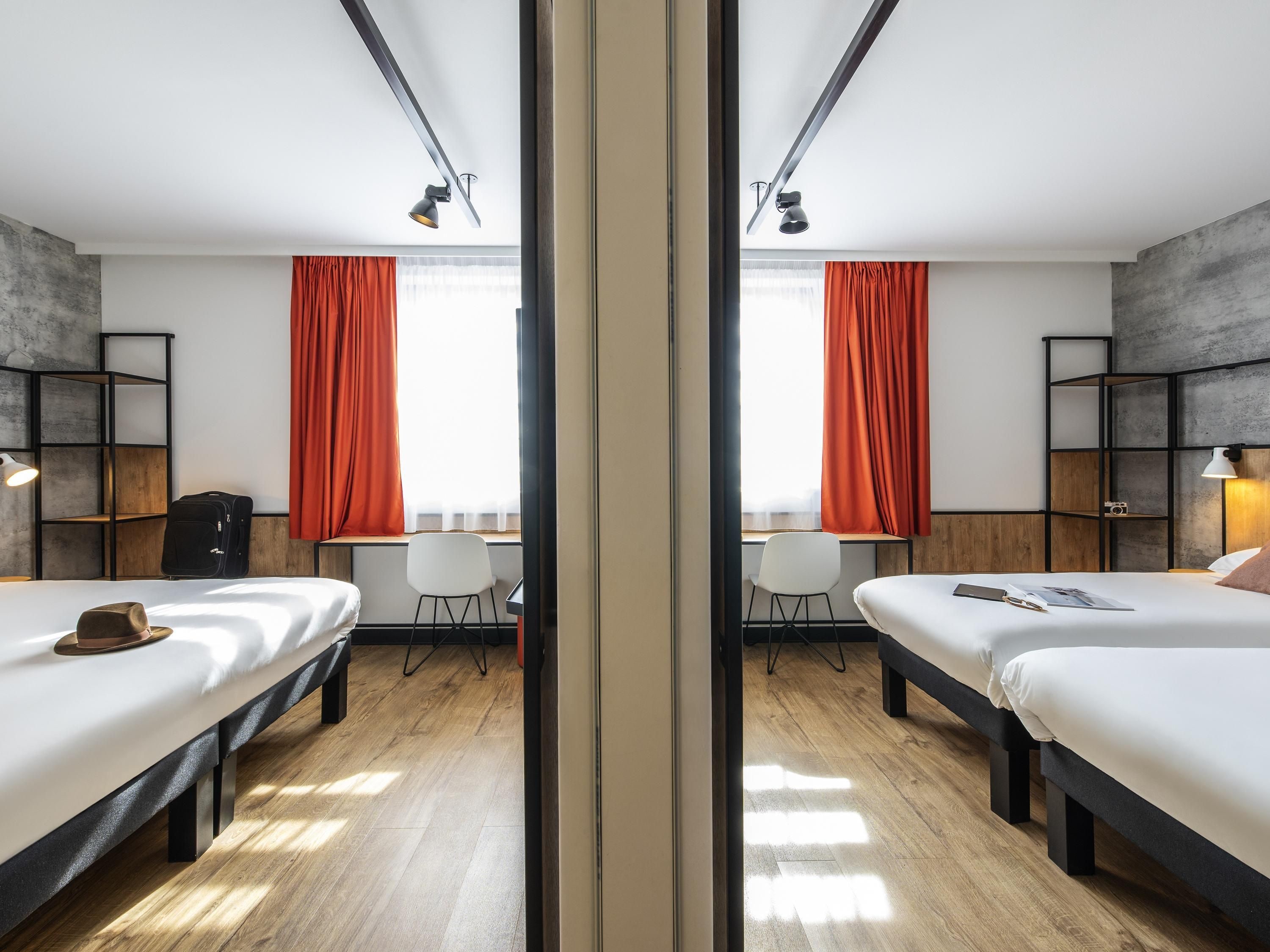 Une pièce aux murs recouverts de miroirs, avec deux lits, un bureau et une chaise.