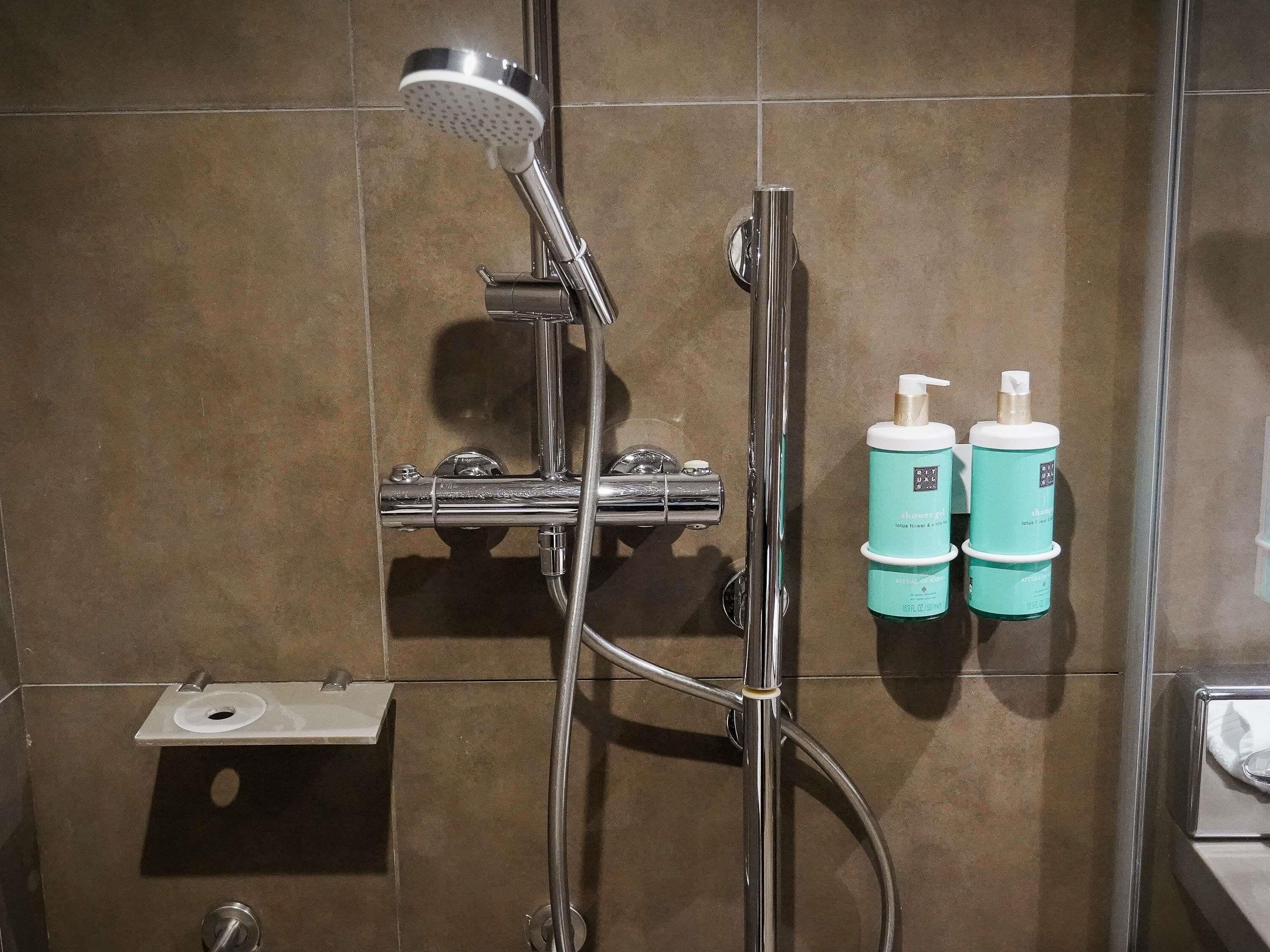 Une salle de bain avec une douche, des toilettes et deux flacons de lotion accrochés au mur.