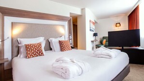 Una habitación de hotel con una cama grande, dos almohadas, un televisor de pantalla plana y una lámpara de pared.