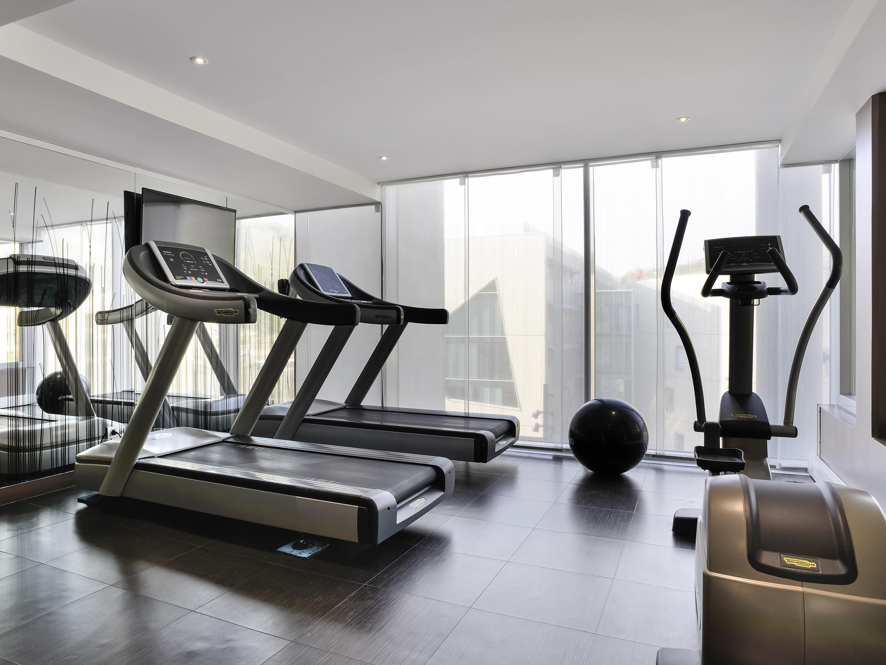 A modern gym with treadmills, ellipticals, and a stationary bike.