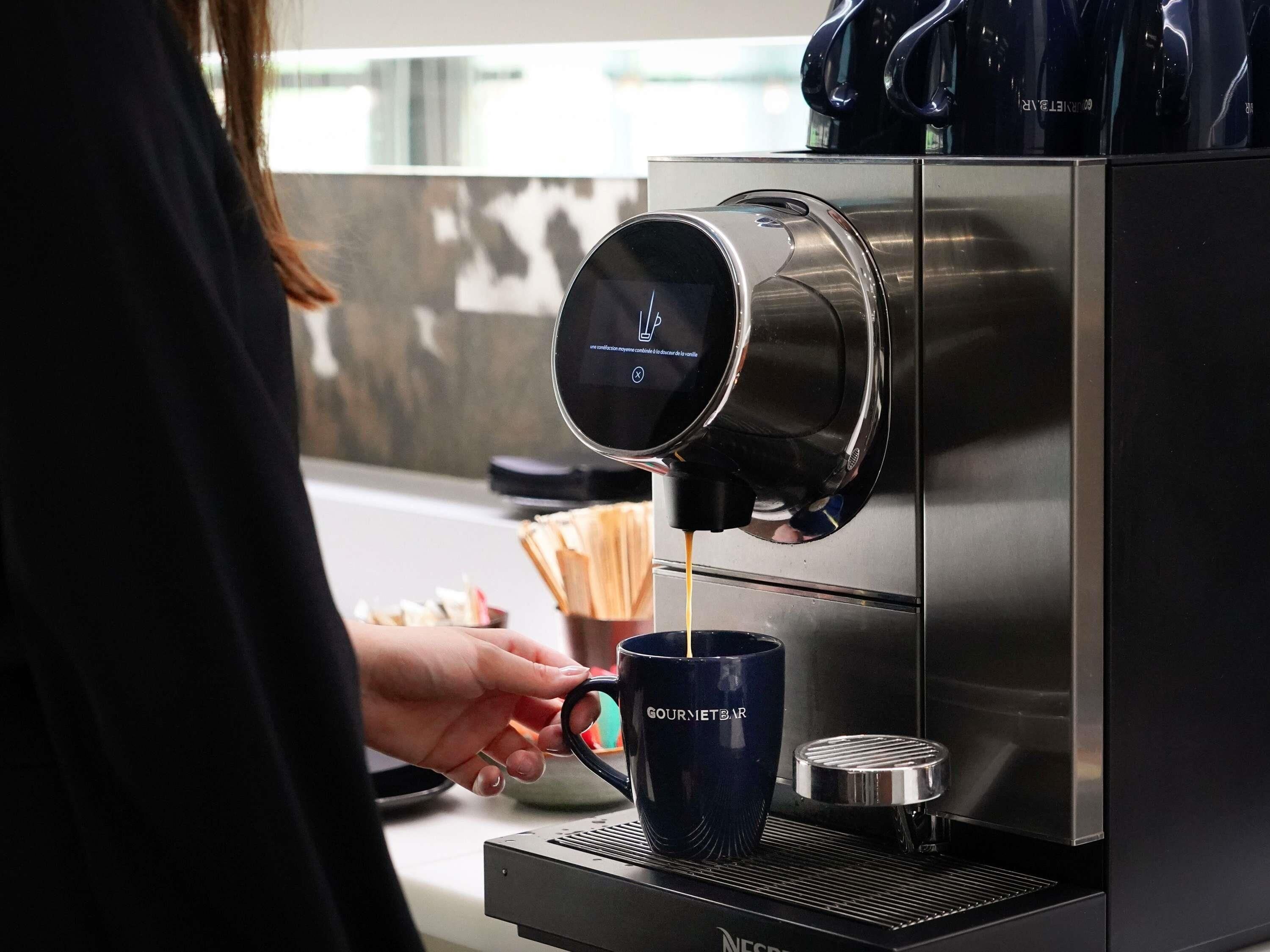 A person operating a coffee machine, dispensing coffee into a mug.