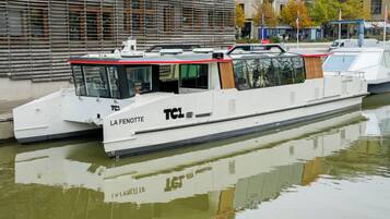 Un barco mercante llamado 'La Fenotte' atracado en un canal, con un edificio moderno al fondo.