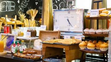 Un bufé de desayuno con diversas opciones de comida, un reloj y un cartel que dice 'Bonjour!'.