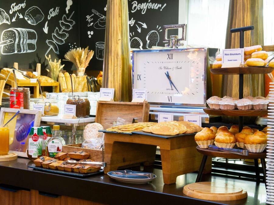 Un bufé de desayuno con diversas opciones de comida, un reloj y un cartel que dice 'Bonjour!'.