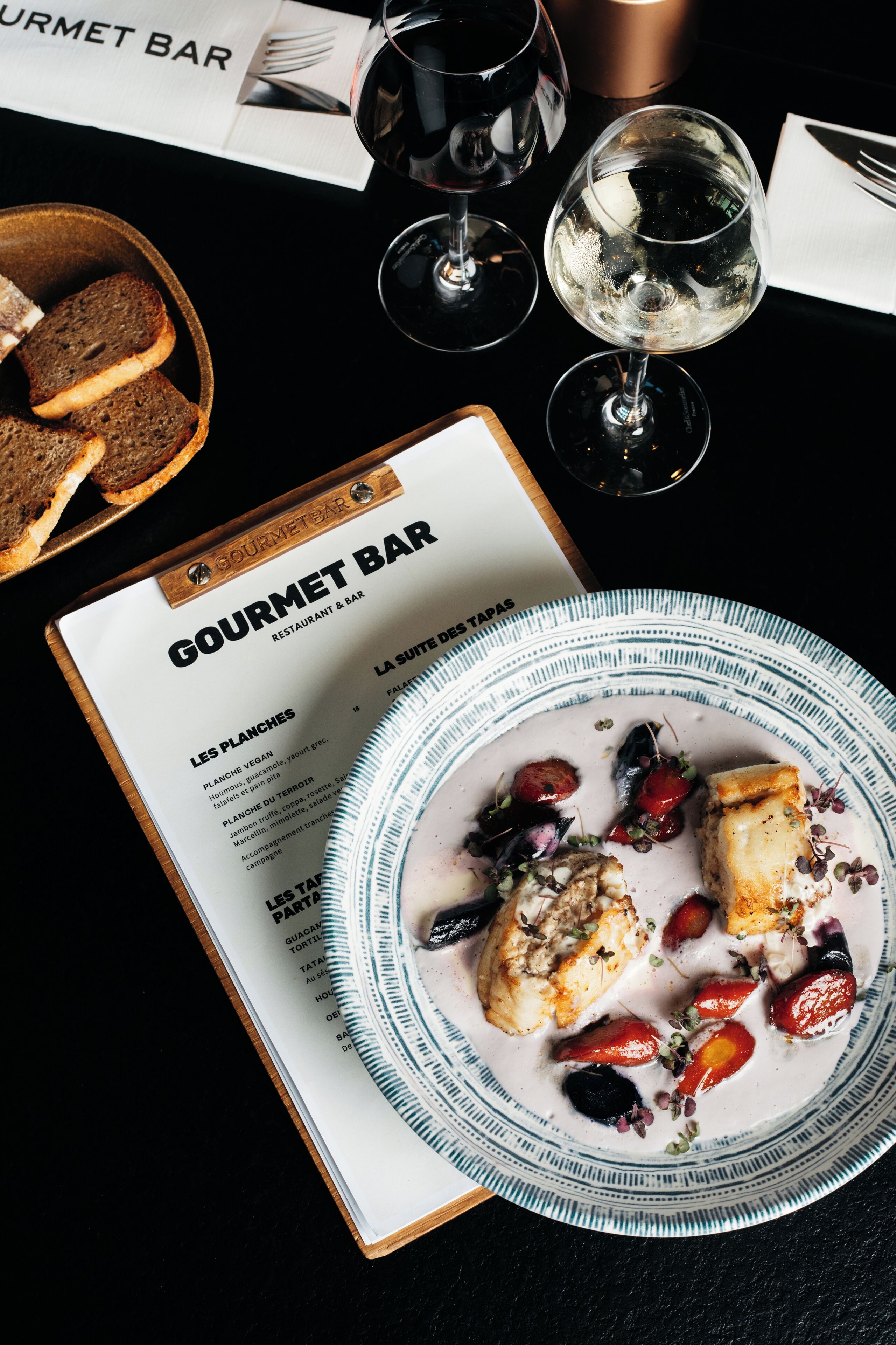 Un menu de restaurant avec une assiette de nourriture, des verres de vin et du pain.