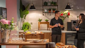 Een moderne keuken met een houten tafel, diverse etenswaren en hangende pendelverlichting.