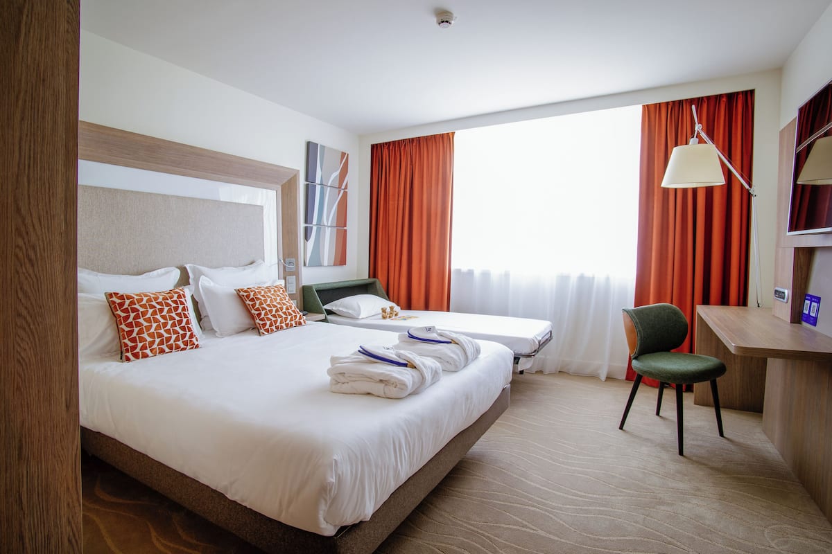Una habitación de hotel con una cama grande, dos camas más pequeñas, un escritorio y una silla.