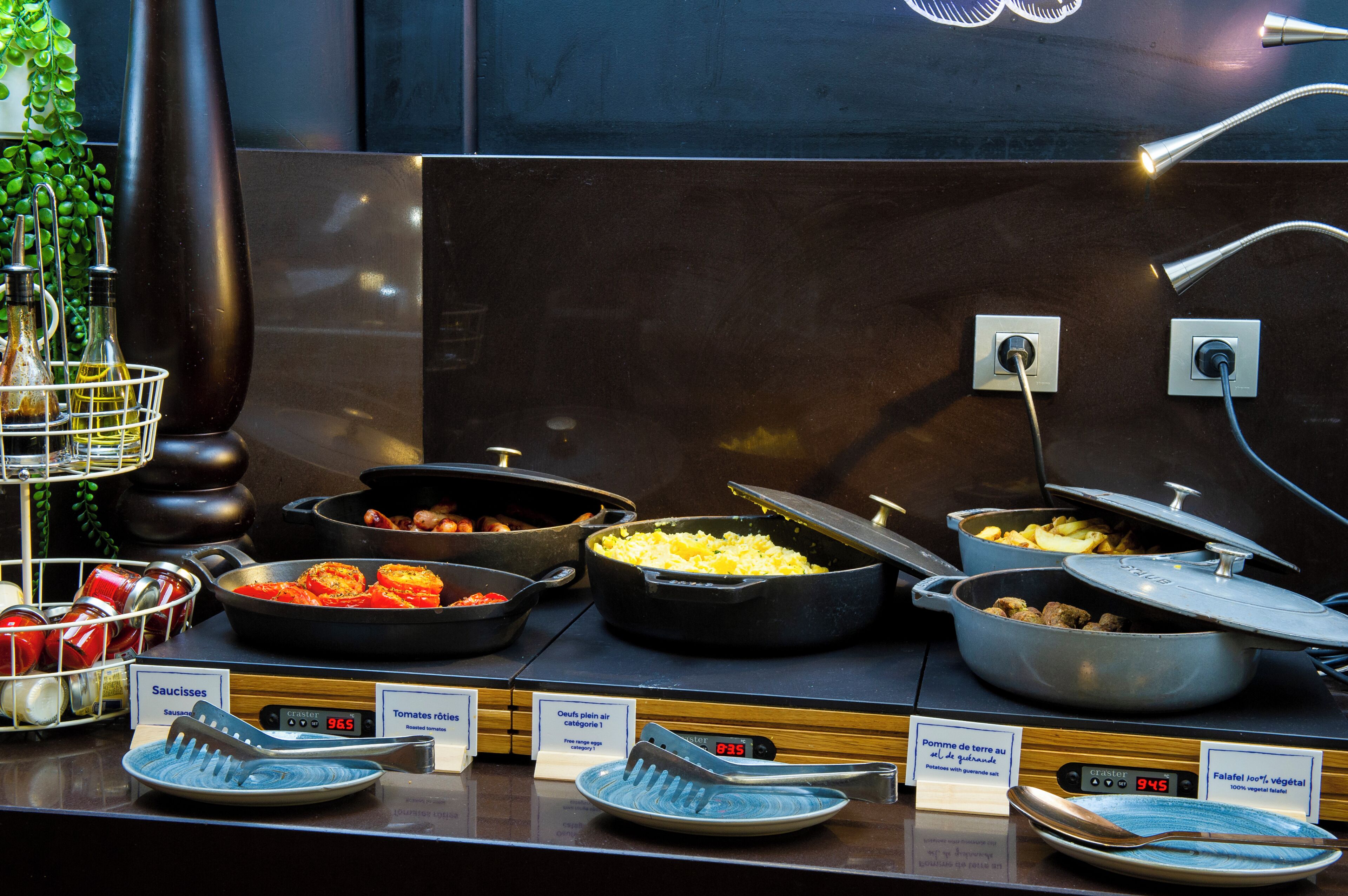 Buffet com diversos pratos, incluindo ovos mexidos, tomates e batatas.