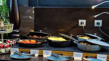 Buffet com diversos pratos, incluindo ovos mexidos, tomates e batatas.