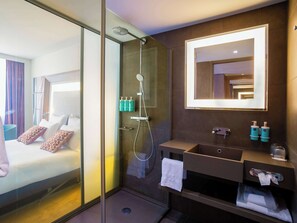 Enjoy a stylish retreat with a spacious bedroom and modern bathroom featuring a contemporary shower, handheld showerhead, and wall-mounted faucet.