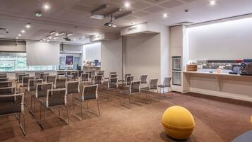Een vergaderruimte met rijen stoelen, een beamer en een presentatiescherm.