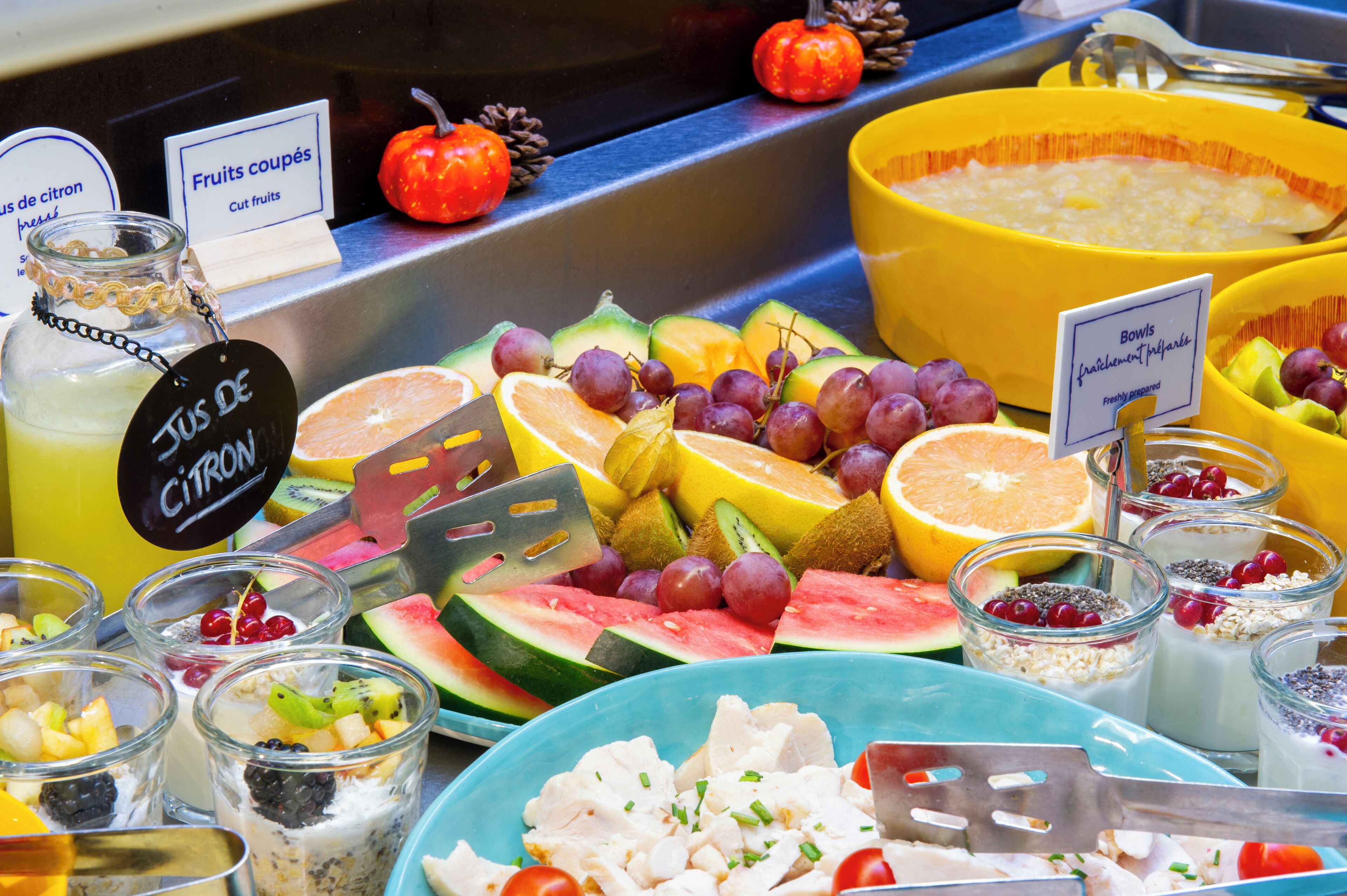 Ein Buffet mit verschiedenen Früchten, Suppenschalen und einem Schild, das frisch zubereitete Schalen anzeigt.
