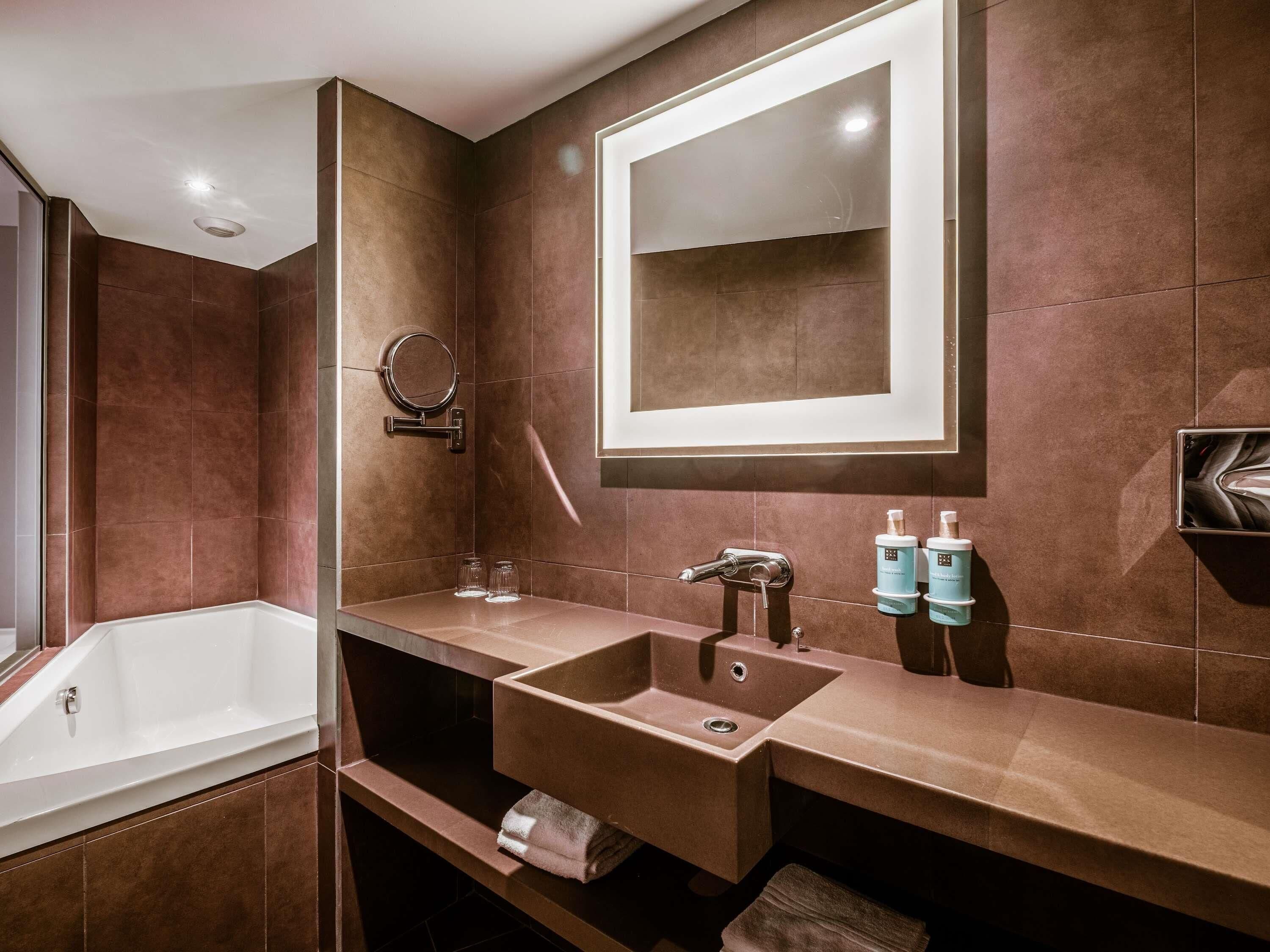 Un baño moderno con una bañera grande, un tocador con espejo y dos lavamanos.