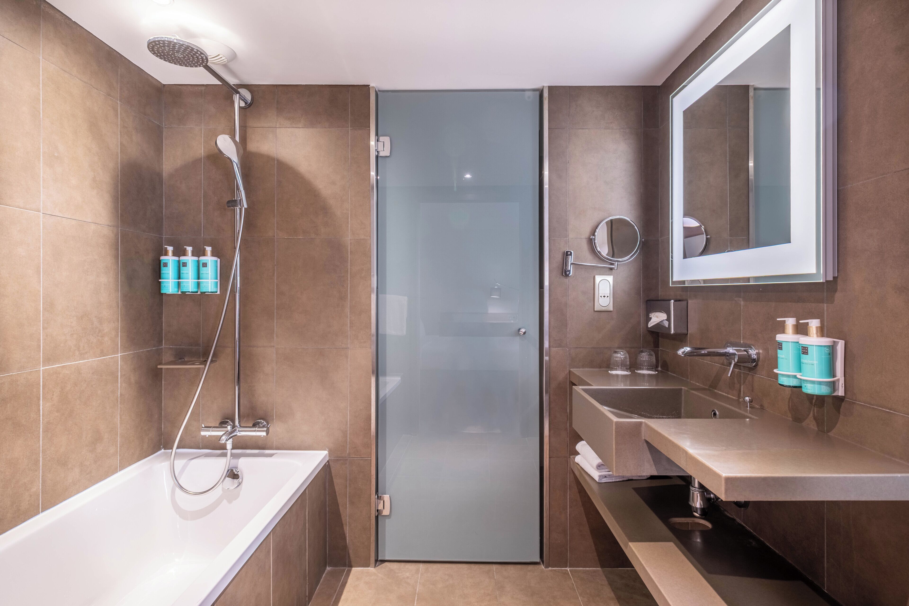 Un baño moderno con cabina de ducha de vidrio, una bañera, un tocador con espejo y dos lavamanos.