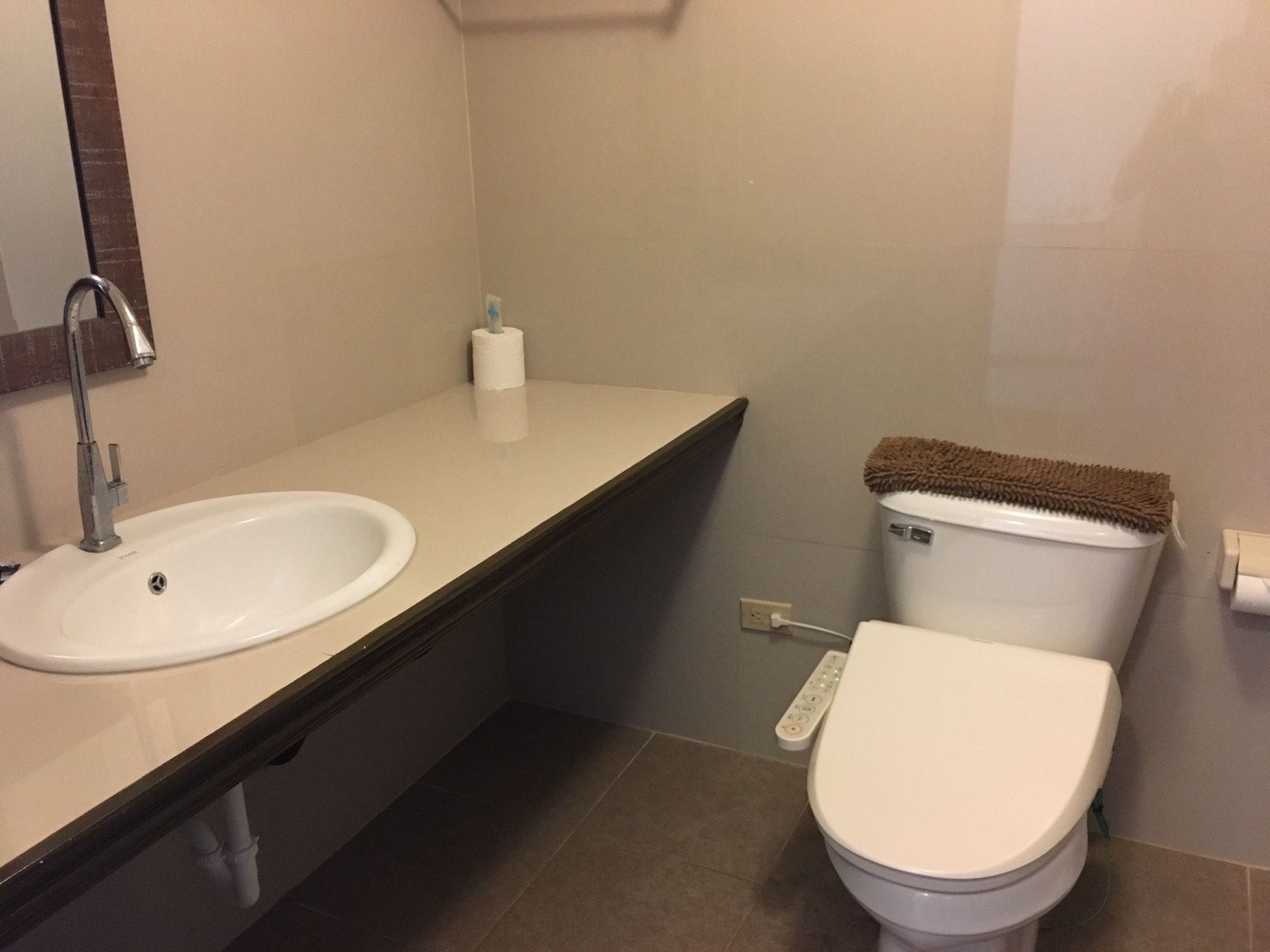 A bathroom with a sink, toilet, and a control panel on the wall.