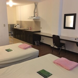 Ein Hotelzimmer mit zwei Betten, einem Schreibtisch, einem Stuhl, einem Waschbecken und einem Spiegel.